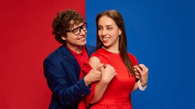 Mutlu, sevgi dolu bir çiftin portresi. Kırmızı ve mavi arka planda sarılıp gülümsüyorlar. İnsan duyguları, ilişkisi, yaşam tarzı kavramı.