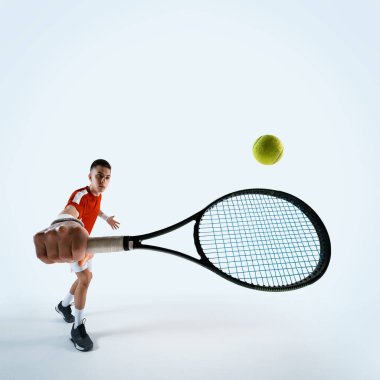 Raket ve topla hareket eden odaklanmış tenisçi, beyaz stüdyo arka planına karşı konsantrasyonla oynuyor. Spor, oyun, turnuva, pratik, gençlik kavramı