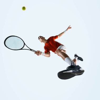Erkeğin düşük açılı görüntüsü, hareket halindeki tenisçi, beyaz stüdyo arka planına karşı güç çevikliği ve kararlılık gösteriyor. Spor, oyun, turnuva, pratik, gençlik kavramı