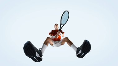 Adamın alt görünüşü, tenisçi iki elinde raket tutarak beyaz stüdyo arka planına karşı harekete geçmeye hazır. Spor, oyun, turnuva, pratik, gençlik kavramı