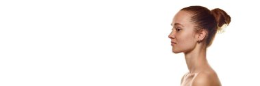 Beyaz arka planda izole edilmiş saçları çekilmiş güzel bir genç kadının yan görüntüsü. Doğal güzellik kavramı, açık ten rengi, cilt bakımı. Pankart. İlan için alanı kopyala.