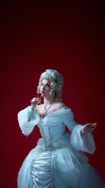 Asil ayin. Kadınlar dramatik bir şekilde şarap kadehinden içerler. Kırmızı arka planda tarihi zarafet ve tuhaflığın ruhunu yakalarlar. Tarihsel portre kavramı, ortaçağ dönemi, karakter.