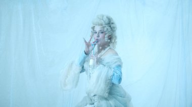 Orta çağ kraliyet mensubu olarak zarif genç bir kadın açık mavi arka planda samanla süt yudumluyor. Zarafet ve absürtlük, mizah ve dönemin kontrastı..