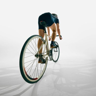 İnsanın arka planı, hareket halindeki bisikletçi, antrenman, azimle bisiklete binme ve beyaz arka plana odaklanma. Spor anlayışı, rekabet, aktif yaşam tarzı, dayanıklılık