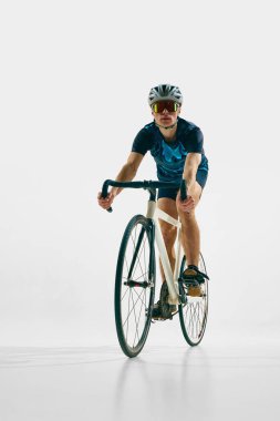 Tam donanımlı genç bir adam, beyaz arka planda izole edilmiş bisiklet süren bir bisikletçi. Spor anlayışı, rekabet, aktif yaşam tarzı, dayanıklılık