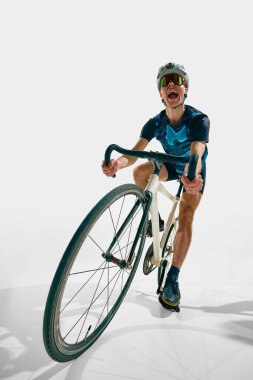 Genç adamın tam boy dinamik görüntüsü, hareket halindeki profesyonel bisikletçi, beyaz arka planda izole edilmiş eğitim. Spor anlayışı, rekabet, aktif yaşam tarzı, dayanıklılık