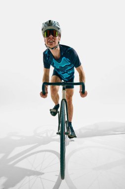 Rekabetçi bir adam, hareket halindeki profesyonel bir bisikletçi, beyaz arka planda tek başına bisiklet sürüyor. Spor anlayışı, rekabet, aktif yaşam tarzı, dayanıklılık