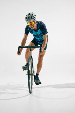 Rekabetçi bir adam, hareket halindeki profesyonel bir bisikletçi, beyaz arka planda tek başına bisiklet sürüyor. Spor anlayışı, rekabet, aktif yaşam tarzı, dayanıklılık