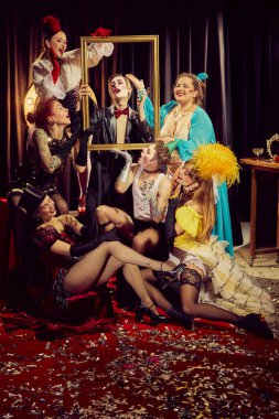 Klasik kıyafetlerle süslenmiş, konfeti kaplı kırmızı halıda poz veren bir grup dışavurumcu kabare sanatçısı. Kabare, gösteri, sirk, retro, vintage, performans konsepti