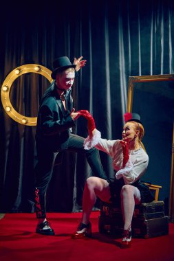 Silindir şapkalı şık kabare ikilisi sahnede sahne ışıkları altında romantik dramatik bir şekilde poz veriyor. Kabare, gösteri, sirk, retro, vintage, performans konsepti.