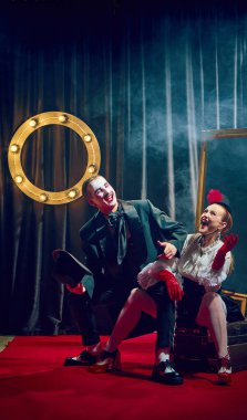 Gülen kabare göstericileri, kadın ve erkek, kırmızı halıda dramatik ifadelerle klasik kostümler içinde poz veriyorlar. Kabare, gösteri, sirk, retro, vintage, performans konsepti.