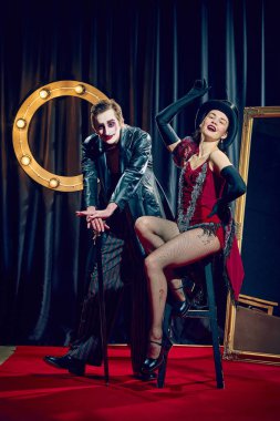 Kabare ikilisi baston ve tabure ile dramatik poz veriyor ve şapka eldiven takıyor klasik makyaj ışıkları. Kabare, gösteri, retro moda, komedi, sahne, performans, ifade, tiyatro kavramı.