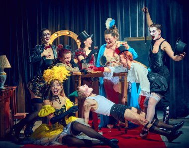 Kabare sanatçıları kaotik, komik sahneler sergiliyor, eğiliyor, gülüyor, kırmızı halıda dramatik bir şekilde poz veriyorlar. Kabare, gösteri ve komedi konsepti, tiyatro performansı, retro, ifade, eğlence