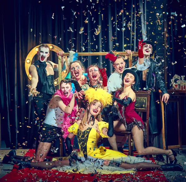 Klasik kostümlü tiyatro sanatçıları konfetilerin düşüşünü, ön planda infaz edilen kadının akrobatik yeteneğini kutluyor. Kabare, gösteri, sirk, retro, vintage, performans konsepti.