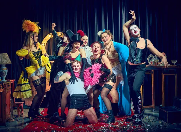 Kabare, konfeti halısında pembe boa ve şapka takan merkezi sanatçının etrafında kahkahalar attı. Kabare, parti, tiyatro, mizah, neşe, kostüm, retro performans, gösteri, sirk.