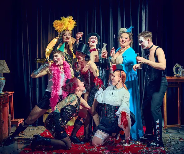 Neşeli kabare kadehleri kırmızı eldivenli şampanya bardakları, korse tüyleri ve konfeti tutuyor. Kabare kavramı, gösteri, retro, kutlama, mizah, tost, performans, parti, gece hayatı.