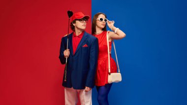 Golf sopalı bir adam ve güneş gözlüğü takan bir kadın kırmızı arka planda şık bir ifadeyle birlikte duruyorlar. Spor anlayışı, insan duyguları, ilişki, yaşam tarzı, moda