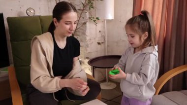 Anne kızıyla oturup gülümsüyor ve elinde bir parça kille mankenlik yapıyor. Yaratıcı bir aktivitede mutlu bir ilişki anı. Çocukluk kavramı, oyun, mutluluk, aile, erken gelişim