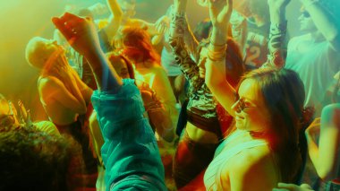 Canlı bir gece kulübünde renkli ışıklarla dans eden enerjik bir kalabalık. Parti anlayışı, gençlik, gece kulübü, kutlama.
