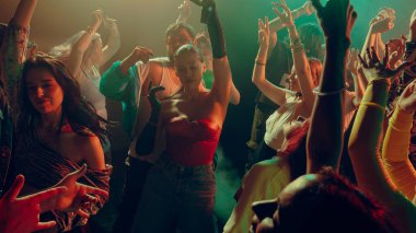 Canlı bir partide renkli ışıklandırmayla enerjik bir şekilde dans eden kalabalık. Parti konsepti, gençlik, gece kulübü, kutlama, konser