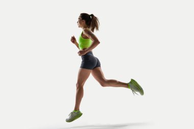 Stüdyo ışığı altında koşuya çıkan güçlü bacaklı ve kollu kadın sporcunun dinamik görüntüsü. Spor, rekabet, aktif yaşam tarzı, dinamik hareket, güç, güven kavramı.