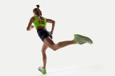 Sportif bir kadının düşük açılı arka planı, hareketli koşucu, beyaz arka plana karşı kararlılıkla antrenman yapıyor. Spor, rekabet, aktif yaşam tarzı, eylem, hareket, hız, performans kavramı.