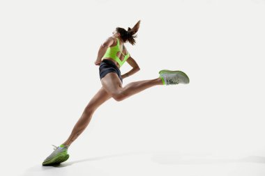 Yüksek atlayışlı atlamadaki atletik kadın, beyaz stüdyo arka planına karşı, enerjik bir hareketle arkadan yakalandı. Spor, rekabet, aktif yaşam tarzı, çeviklik, denge, güç kavramı