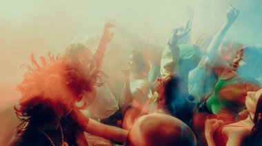 İçerde renkli ışıklandırmayla dans eden bulanık kalabalık. Konser, parti, müzik, ritim kavramı.