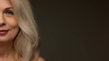 Yüzü yumuşak makyajlı, cilt rengi koyu mod arka planına karşı gülümseyen ve mesaj eklemek için negatif alan arayan son sınıf öğrencisi. Pankart. Kaldırma etkisi kavramı, sağlıklı cilt, güzellik, ameliyat