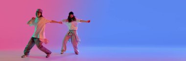 Kendine güvenen genç bayan dansçılar pembe ve mavi ışıklar altında eklemek için negatif alana sahip değişken arkaplanlara karşı senkronize hareket ediyorlar. Pankart. Müzik, ritim ve anlamlı stil kavramı.