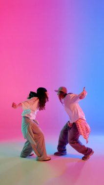 Canlı stüdyo ışıkları altında dans eden şehirli kızlar hip hop tarzında rengarenk arka plana karşı. Dinamik fotoğraf. Müzik, ifade, ritim ve hareketli enerji kavramı.