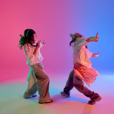 Pembe ve mavi neon ışıkların altında dans eden iki yetenekli ve artistik kız arkaplanda hip hop yapıyor. Tarz, ritim ve koordineli sokak hareketi kavramı.