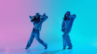 İki genç dansçı, kızlar arka planda yumuşak pembe ve turkuaz ışıklar altında hip hop koreografisi eğitiyorlar. Müzik enerjisi kavramı, takım çalışması, yaratıcılık ve dans ilerlemesi.