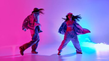 Yaratıcı ve yetenekli genç kızlar, büyük beden kıyafetler giyip, serbest dans ederek, parlak neon ışığı vurgu hareketleriyle, arka plana doğru ilerliyorlar. Müzik kavramı, ritim