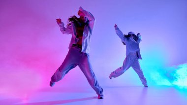 Havada hoplayıp zıplayan şık giyinmiş kızlar mavi dumanlı canlı ışık altında serbest dans ediyorlar. Müzik, coşku, ifade ve yaratıcı fiziksel özgürlük kavramı.