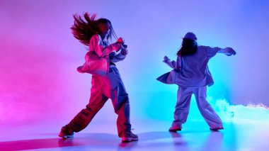 Yetenekli hip hop ikilisi dumanlı pembe ve turkuaz ışıklar altında arkaplana karşı akıcı ve güçlü dans ediyor. Disiplin, müzik, güç ve dışavurumcu hareket kavramı