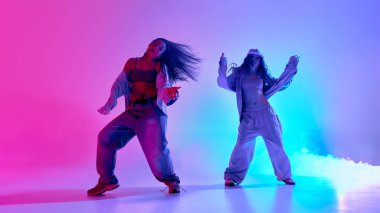 Yaratıcı bayan dansçılar, hip hop seansı sırasında gradyan arkaplana karşı renkli sis dolu alanda neşeli bir koordinasyon sergiliyorlar. Müzik kavramı, gençlik özgürlüğü, tarz ve dinamik ritim.