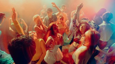 Renkli ışıklandırma atmosferinde dans eden çeşitli grupların olduğu canlı bir parti sahnesi, neşe ve kutlama gösterisi. Gece hayatı kavramı, parti, gençlik, yaz, şenlik