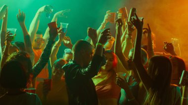 İnsanların dans ettiği ve renkli ışıklar altında kutlama yaptığı canlı bir parti sahnesi. Gece hayatı kavramı, parti, gençlik, yaz, şenlik, kutlama