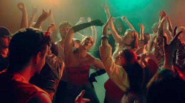 Renkli ışıkları olan bir gece kulübünde enerjik bir şekilde dans eden bir grup insan. Gece hayatı partisi kavramı, gençlik, yaz, şenlik, kutlama