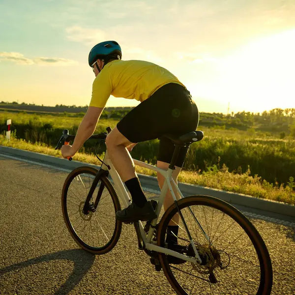 Motosiklet sürücüsünün hareket halindeki ritim ve kararlılığı ve sakin kırsal alandaki virajları arka açıyla izlemesi. Spor anlayışı, bisiklet, sağlıklı yaşam tarzı, dayanıklılık, doğa.