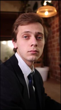 Siyah takım elbiseli şık bir genç modern ofiste oturuyor, çevrimiçi çalışırken dizüstü bilgisayara odaklanıyor, kendine güveni ve profesyonel tutumu var. İş kavramı, yatırımlar, uzaktan çalışma.