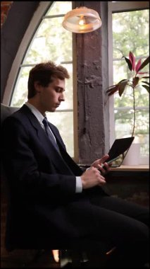 Siyah takım elbiseli şık bir adam, teneffüste akıllı telefon ekranına göz atar. Çağdaş ofis ortamında iş meseleleriyle bağlantısını koparmaz. İş kavramı, yatırımlar.