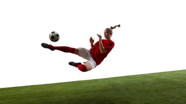 Kırmızı futbol üniformalı bir kız, sert bir saldırı sırasında, yeşil çimenli oyun parkında beyaz arka plana karşı tüm vücudunu esneterek havada uçuyor. Spor, yoğunluk, eylem, performans, enerji kavramı