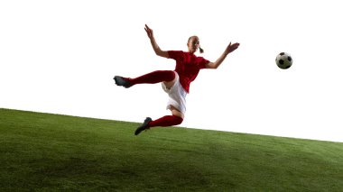 Topa vuran bayan atlet, yeşil çimenli oyun parkında beyaz arka planda hareketli bir poz veriyor. Spor, güç, odaklanma, hareket, rekabet kavramı