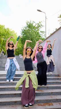 Genç dansçılar sokak gösterileri sırasında şehir merdivenlerinde dinamik pozlar veriyorlar. Kentsel sanatsal ifade ve gençlik coşkusu kavramı.