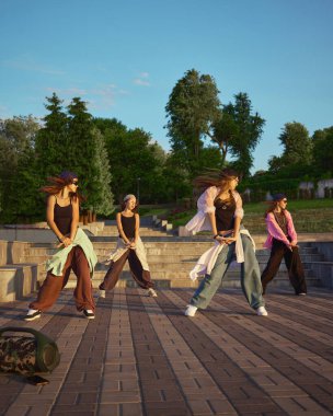 Bir sokak dansı grubu, şehir parkı ortamında çeşitli yetenekler sergileyerek enerjik bir gösteri sergiliyor. Kentsel gençlik kültürü ve ifadesi kavramı.