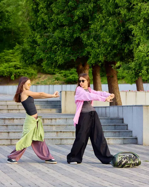 İfade özgürlüğü. Güneşli park ortamında sokak dansı pratiği yapan iki kız. Kentsel fitness kavramı, özgürlüğün yaratıcı ifadesi