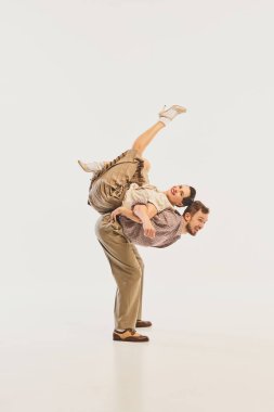 Dinamik bir retro dans performansı, tarafsız bir arkaplana karşı akrobatik poz veren klasik giyimli bir çifti sergiliyor. Sahne sanatlarında nostalji kavramı.