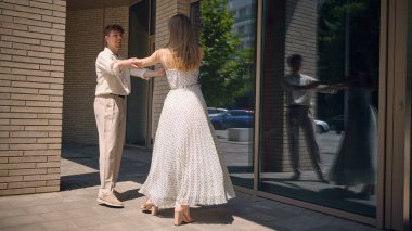 Birkaç uygulama modern bir binanın dışında cam yansımalarla dans ediyor, kent hayatına zarafet ve mimariye sanat katıyor. Modern mimariyle dans kavramı kesişiyor..